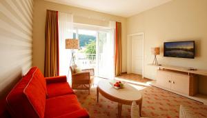 a living room with a red couch and a table at Landhotel Sanct Peter in Bad Neuenahr-Ahrweiler