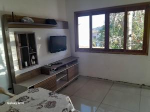 a living room with a tv and a window at Pousada do caminho in Águas da Prata