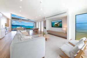 a living room with white furniture and the ocean at Coastal Haven Retreat - Luxe Airlie Beach Holiday Home in Airlie Beach
