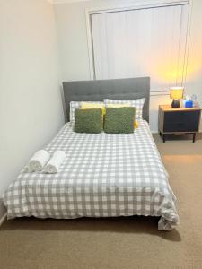 a bedroom with a bed with a checkered blanket and pillows at Jordan Springs - Home in Kingswood