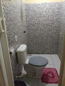 a bathroom with a toilet and a tiled wall at Hotel Ramos in Barreirinhas