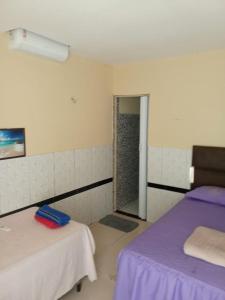 a room with two beds and a door to a shower at Hotel Ramos in Barreirinhas