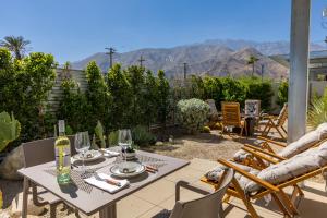 a patio with a table and chairs with mountains in the background at House of Light by ACME House Company in Palm Springs