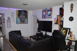 a living room with a black leather couch and a flat screen tv at Drip Star Life Hostel Miami 3 in Parkway Regional Medical Center Heliport