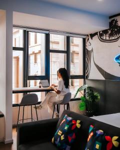 una mujer sentada en un escritorio con una computadora portátil en Ceylonz Leisure Suites KLCC Bukit Bintang, en Kuala Lumpur