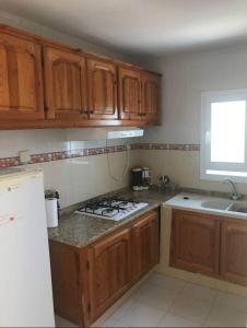 a kitchen with wooden cabinets and a stove top oven at Near the Beach Apt in Aghīr