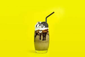 a milkshake with a straw on a yellow background at Hotel Lucca in Legazpi