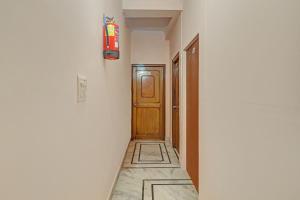 ガーズィヤーバードにあるHotel O Satguru Residencyの木製の扉と消火器のある廊下