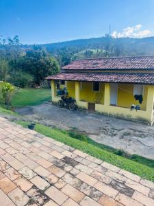 ein gelbes Haus mit einem Motorrad, das davor geparkt ist in der Unterkunft Sítio do Ademir in Jaboticatubas