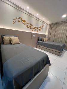 a bedroom with two beds and a painting on the wall at Flat 400m da Praia de Muro Alto - 302C Malia Beach in Ipojuca +106 photos