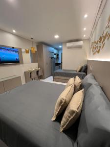 a bedroom with a bed with pillows and a tv at Flat 400m da Praia de Muro Alto - 302C Malia Beach in Ipojuca