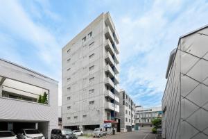 a tall white building on a street with parked cars at J-star 901 in Sapporo