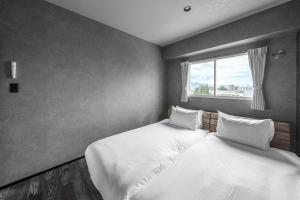 two twin beds in a room with a window at J-star 901 in Sapporo