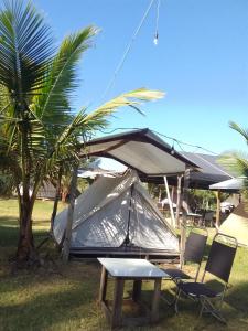 a tent with two chairs and a table and a palm tree at Eco Beach Can GIo in Kon Rung (1)