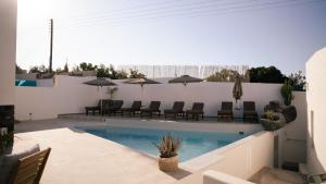 a swimming pool with chairs and umbrellas on a patio at Noir Santorini in Monolithos