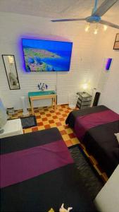 a bedroom with two beds and a tv on the wall at Recamara Alan en Zona Romantica Departamento compartido con el host in Puerto Vallarta