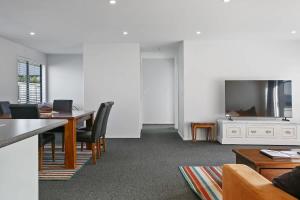 a living room with a table and a tv at Huka Falls Getaway (Family escape) in Taupo