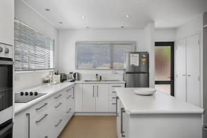 une grande cuisine blanche avec comptoirs et appareils blancs dans l'établissement You little beauty - Wharewaka Beach Magic, à Taupo