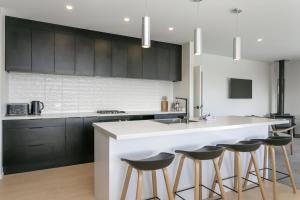 eine Küche mit einer weißen Theke und schwarzen Schränken in der Unterkunft Sophistication Meets Relaxation in Taupo