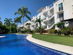 a swimming pool in front of a building at Marina Diamante Victory in Acapulco
