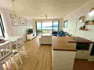 a kitchen and living room with a view of the ocean at Heavenly Views in Airlie Beach