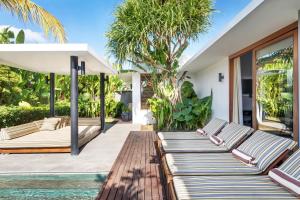 a row of chaise lounge chairs on a patio with a pool at Amarin Seminyak in Seminyak