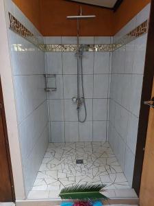 a shower in a bathroom with a tile floor at Villa Nina in Taputapuapea +2 photos
