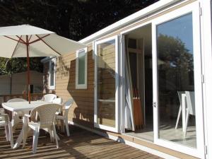 una casa con mesa, sillas y sombrilla en Mobil-home 10 pers, 4 ch, terrasse - Avrillé - API-1-52-568, en Avrillé