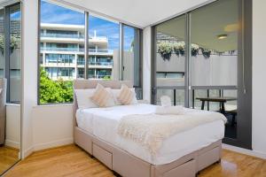 Un dormitorio con una cama grande y grandes ventanales. en Rosebery Spacious 2Br Apt Near CBD Free Parking, en Sídney