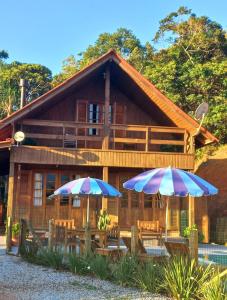 a house with two umbrellas in front of it at Recanto Paraíso da Colina in Santo Amaro da Imperatriz