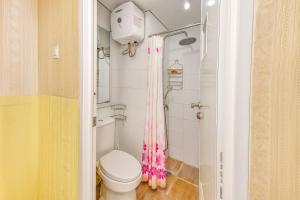 a bathroom with a toilet and a pink shower curtain at Quintessa Room at Candiland Apartment in Jomblang