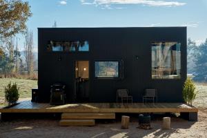 a black house with two chairs and a wooden deck at Nestled Cabins in Verdun