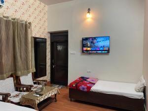 a room with two beds and a tv on the wall at Hotel Vacation in Jaipur