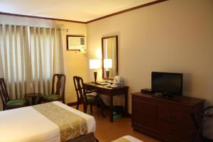 a hotel room with a bed and a desk with a television at East Asia Royale Hotel in General Santos