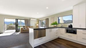 una cucina con mobili bianchi e un soggiorno di Tepuia Cottage - Havelock Holiday Home a Picton Altre 14 foto