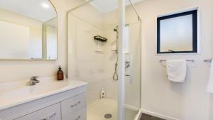 un bagno bianco con doccia e lavandino di Tepuia Cottage - Havelock Holiday Home a Picton