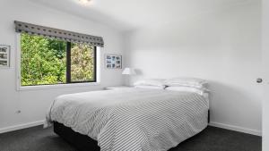 a white bedroom with a bed and a window at Pukawa Bliss - Pukawa Holiday Home in Kuratau