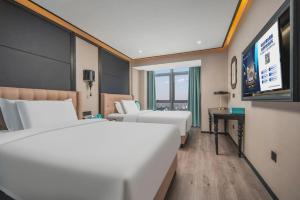a hotel room with two beds and a flat screen tv at Xana Hotelle Nanchang Gaoxin Xincheng Wuyue Plaza in Nanchang +257 photos