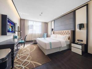 a hotel room with a large bed and a desk at Xana Hotelle·Yutian in Tangshan