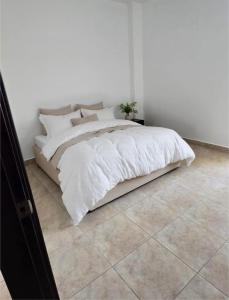 un letto bianco in una camera da letto bianca con pavimento piastrellato di Elegante apartamento con Golf, Restaurantes y Spa a ArraijÃ¡n