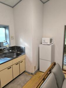 a kitchen with a sink and a microwave on top of a refrigerator at Summer Cool Forest Cottage-北軽井沢 夏涼の森コテージ- in Tsumagoi +8 photos