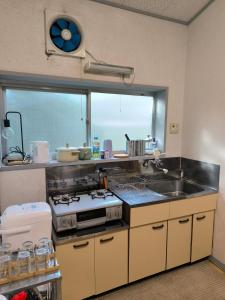 a kitchen with a stove and a sink and a window at Summer Cool Forest Cottage-北軽井沢 夏涼の森コテージ- in Tsumagoi