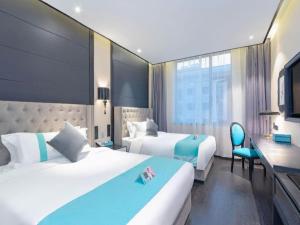 a hotel room with two beds and a desk at Xana Hotelle Xi'an Zhonglou Luoma in Xi'an