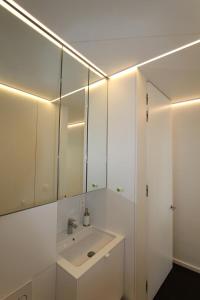 a white bathroom with a sink and a mirror at Studio Zeezicht in Ostend