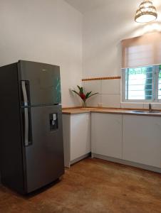 a kitchen with a stainless steel refrigerator and white cabinets at Quédate Aquí También in Las Galeras