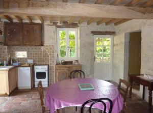 a kitchen with a table with a purple table cloth on it at Gite Rural de Caractere in Guérin