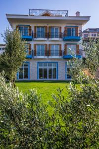 an apartment building with a balcony on a lawn at Clementin Suits Sigacık in Siğacık