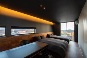 a bedroom with two beds and a table and windows at Awaji-shima C-Side Hill Top Terrace - Vacation STAY 88185v in Minamiawaji