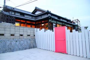 a house with a red door behind a white fence at Okamuran Shimanami Goten - Vacation STAY 95664v in Imabari +10 photos