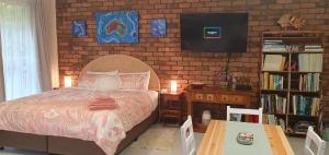 a bedroom with a bed and a brick wall at Ultima Thule Studio, South Durras in Durras
